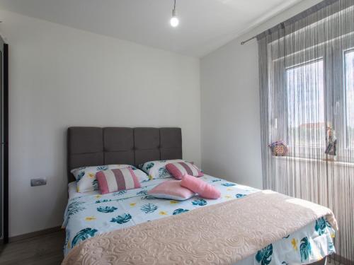 um quarto com uma cama com almofadas cor-de-rosa e uma janela em Apartments with a parking space Kastel Stari, Kastela - 22590 em Kaštela