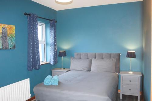 a bedroom with a large bed with blue walls at Riverside Cottage in the Burren in Corrofin