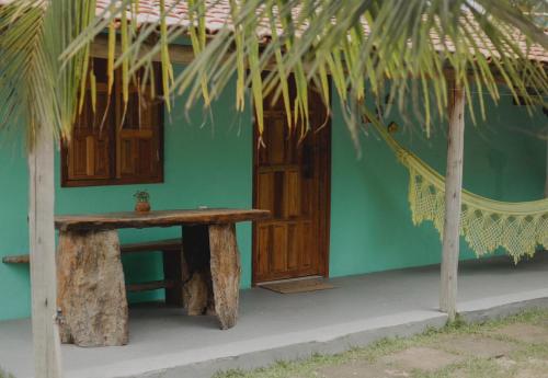 a green house with a bench in front of it at Casa 02 na villa uryah in Caraíva