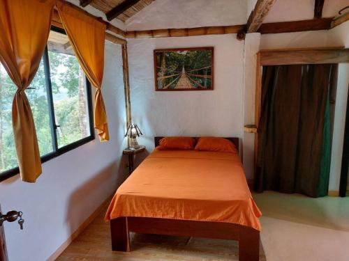 a bedroom with a bed with an orange blanket at Casa Ariana, Acepto Mascota in Ayampe