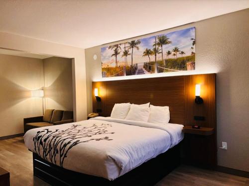 une chambre d'hôtel avec un lit et une photo de palmiers dans l'établissement Clarion Pointe Lakeland I-4, à Lakeland