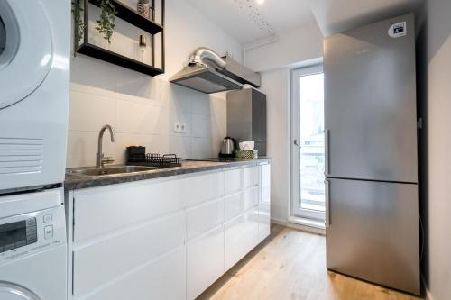 a kitchen with white cabinets and a stainless steel refrigerator at Breeze - Lovely Apartment in Aviatiei with Parking in Bucharest