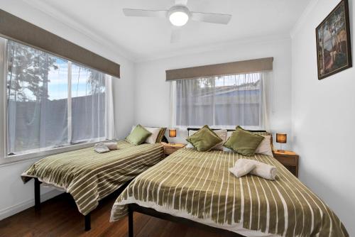 two beds in a room with two windows at Long Island Beach House gateway to Mornington Peninsula #free parking in Frankston