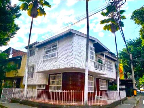ein weißes Haus mit zwei Palmen davor in der Unterkunft Hostel Cocoon la 70 in Medellín