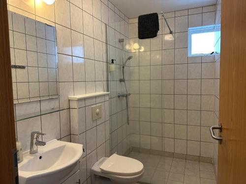 a white tiled bathroom with a toilet and a sink at Hotel Kanslarinn Hella in Hella