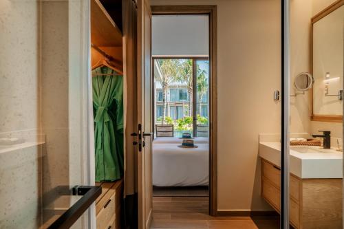 - Baño con puerta que conduce a un dormitorio en The Ocean Resort Quy Nhon by fusion, en Quy Nhon