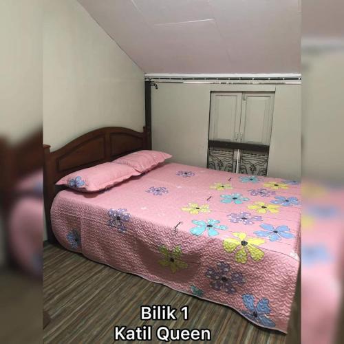 a bedroom with a bed with a pink comforter at Serambi Homestay Kangar in Kangar