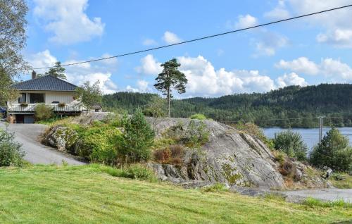 a house on a hill next to a large rock at Beach Front Apartment In Øyslebø in Marnardal