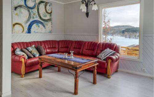 a red couch in a living room with a table at Beach Front Apartment In Øyslebø in Marnardal