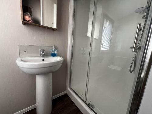 a white bathroom with a sink and a shower at 6 Berth Caravan With Stunning Sea Views And Decking To Relax On, Ref 32048az in Lowestoft