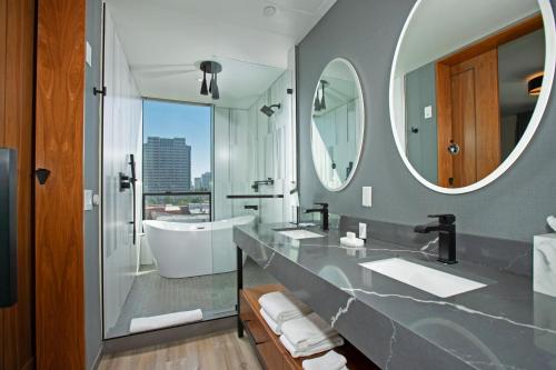 baño con 2 lavabos y espejo grande en The Glenmark, Glendale, a Tribute Portfolio Hotel, en Glendale