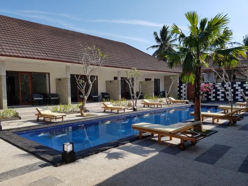 a swimming pool with chaise lounges and a resort at Villa Pine Tree in Gili Trawangan
