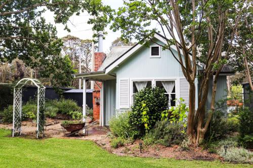 ein weißes Haus mit einem Baum im Hof in der Unterkunft The Old Cottage - Country Couples Retreat in Tomerong