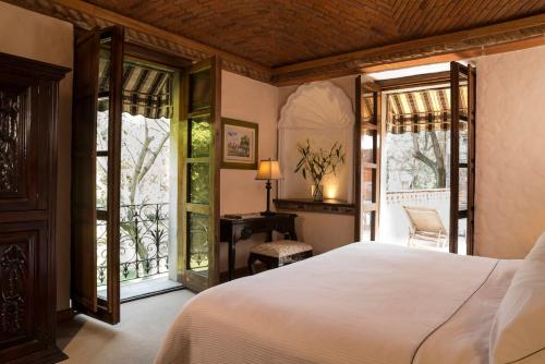 um quarto com uma cama, uma secretária e janelas em Fiesta Americana Hacienda San Antonio El Puente Cuernavaca em Cuernavaca