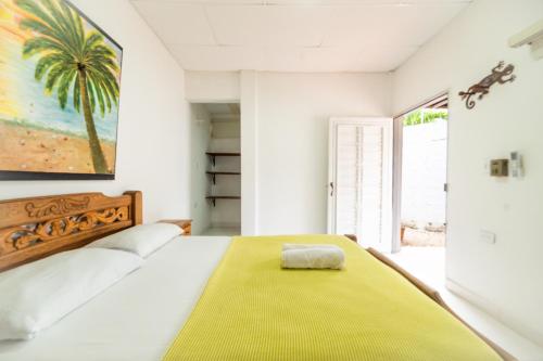 een slaapkamer met een groot bed en een gele deken bij Hostal del Mar - Tolu in Tolú