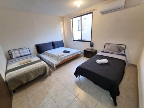 Habitación con 2 camas, sofá y ventana en Casa muy Ubicada Amplia con alberca Montejo SD, en Querétaro