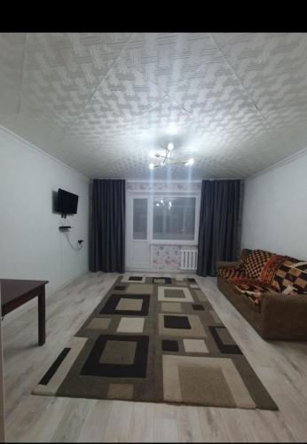 ein Wohnzimmer mit einem Sofa und einem Tisch in der Unterkunft Двухкомнатная квартира на юго-востоке г.Караганда in Qaraghandy