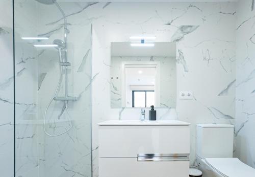 a white bathroom with a shower and a sink at Stay U-nique Apartments Albeniz BCN in Hospitalet de Llobregat