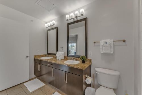 a bathroom with two sinks and a toilet and mirrors at Elegant 2br Apartment I Pool I Gym I Parking Cs in Dallas