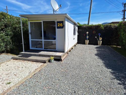 a small house with a door on a gravel driveway at Picton's Waikawa Bay Holiday Park in Picton
