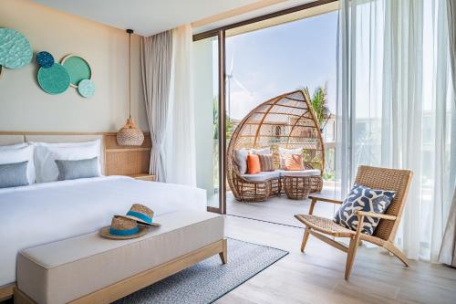 a hotel room with a bed and a chair at The Ocean Resort Quy Nhon by fusion in Quy Nhon