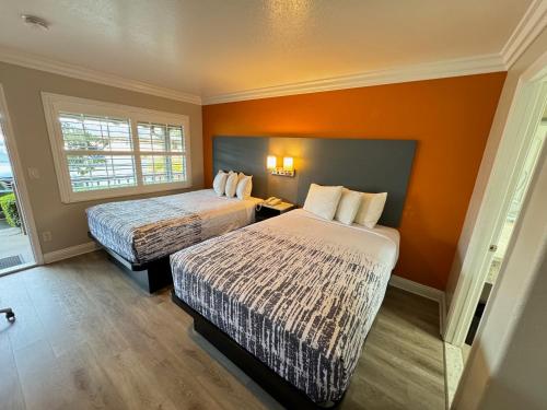 Habitación de hotel con 2 camas y pared de color naranja en Padre Oaks, en Monterey