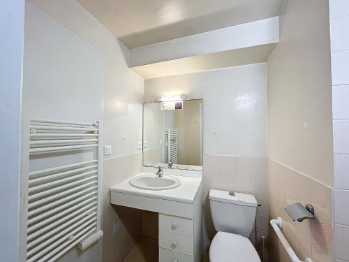 uma casa de banho com um WC, um lavatório e um espelho. em Studio Lamalou-les-Bains, 1 pièce, 2 personnes - FR-1-451-67 em Lamalou-les-Bains