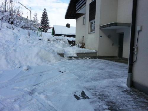 a driveway covered in snow next to a house at Elfe - Apartments Three-bedroom Apartment for 6 guests with patio in Emmetten