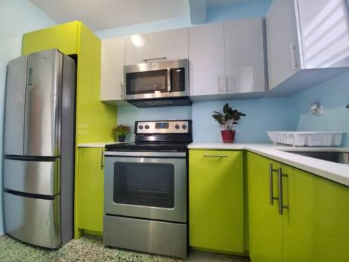 a kitchen with green and white cabinets and a refrigerator at Casa Laguna Unit 6, Spacious 3BR Near Beach and Restuarants in San Juan