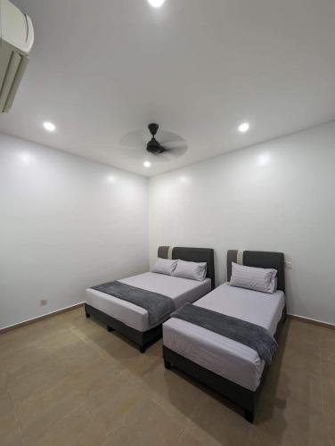 two beds in a room with a ceiling at D’Garden Cottage with big field in Kluang