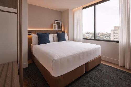 a bedroom with a large bed with a large window at Rydges North Sydney in Sydney