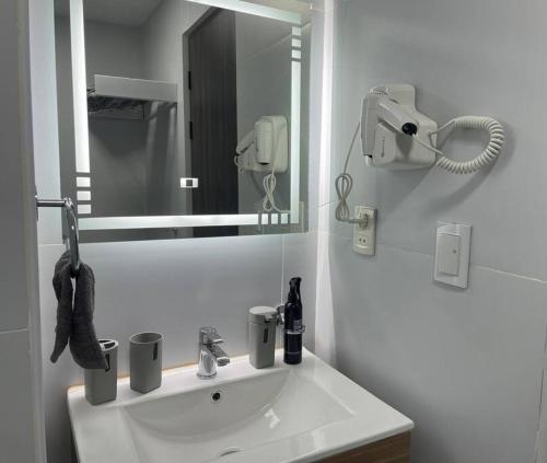 Baño blanco con lavabo y espejo en Apartamento céntrico y panorámico en La Paz, en La Paz