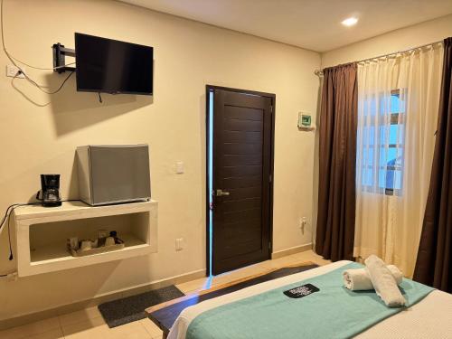 a room with a bed with a tv and a door at Suites Valentina in Puerto Morelos