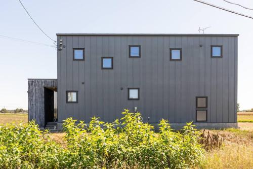 a gray building with a door in a field at One house Naganuma MAOI in Naganuma