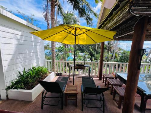 eine Terrasse mit einem Tisch und Stühlen sowie einem gelben Regenschirm in der Unterkunft The White Palace Koh Sdach in Kaoh Sdach
