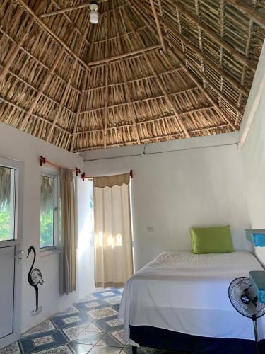 a bedroom with a bed and a straw roof at Cuarto Palma in El Paredón Buena Vista