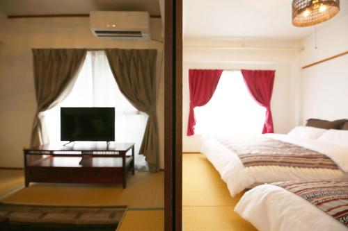 a bedroom with a bed and a tv and a window at 高原マンション 201 in Horinouchichō