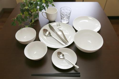 a table with white plates and silverware on it at 高原マンション 201 in Matsuyama