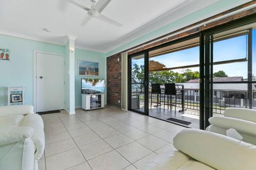 a living room with white furniture and a balcony at Bongaree Water's View in Bongaree