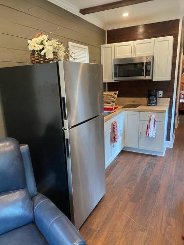 a kitchen with a stainless steel refrigerator and white cabinets at Tiny House Oasis Nature Escape Unit A in Nacogdoches
