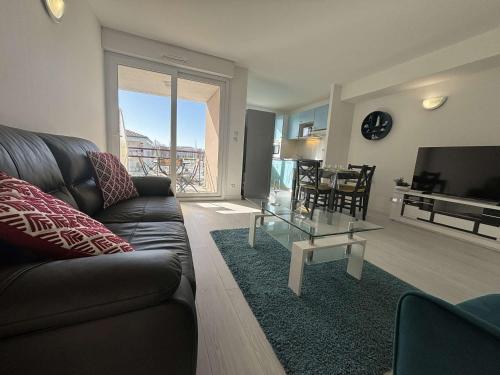 un salon avec un canapé et une table en verre dans l'établissement Spacieux appartement 2 chambres avec parking à Rochefort - FR-1-246B-50, à Rochefort