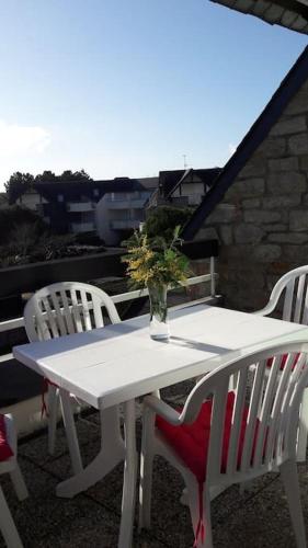une table et des chaises blanches avec un vase. dans l'établissement BRIGHT AND QUIET APARTMENT 5 MNS FROM THE BEACH, à Carnac