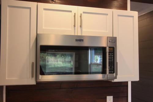 una cucina con forno a microonde e armadietti bianchi di Tiny House Oasis Nature Escape Unit A a Nacogdoches