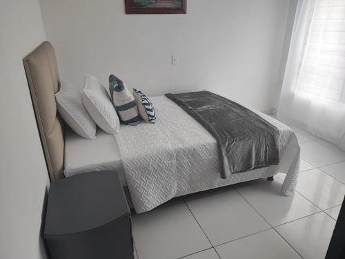 a white bedroom with a bed and a chair at Habitación en encantadora casa en Itagui in Itagüí