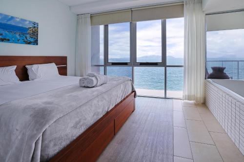 a bedroom with a bed with a view of the ocean at Best at Bright Point Absolute Waterfront Apartment in Nelly Bay