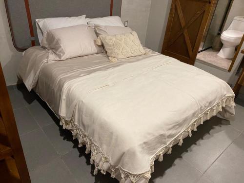 a bed with white sheets and pillows in a room at Layoo, Tu Casa en Oaxca 105 in Oaxaca City