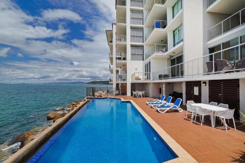 a swimming pool in front of a building next to the ocean at Best at Bright Point Absolute Waterfront Apartment in Nelly Bay