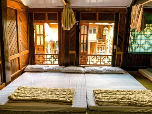 1 cama blanca grande en una habitación con ventanas en Eco Homestay Mai Chau - Venuestay, en Mai Chau