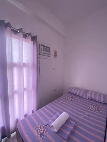 a bedroom with a purple bed with a window at Three U's Pension House in Palompon