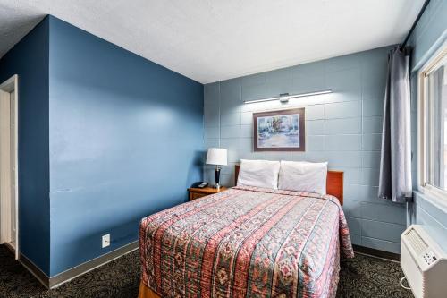 a blue room with a bed with a bedspread and a window at Broadway Inn in Council Bluffs